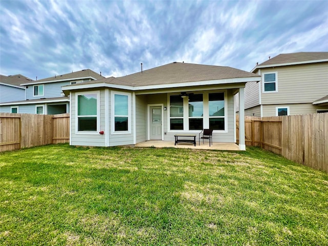 rear view of property with ceiling fan, a yard, and a patio area