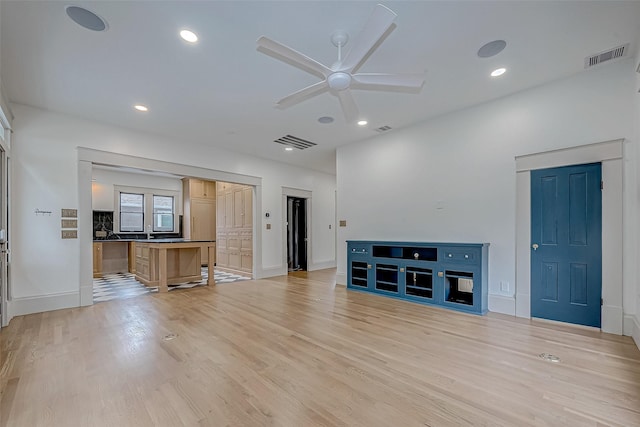 unfurnished living room with ceiling fan and light wood-type flooring