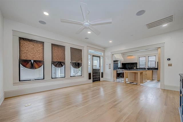 unfurnished living room with a wealth of natural light, ceiling fan, and light hardwood / wood-style flooring