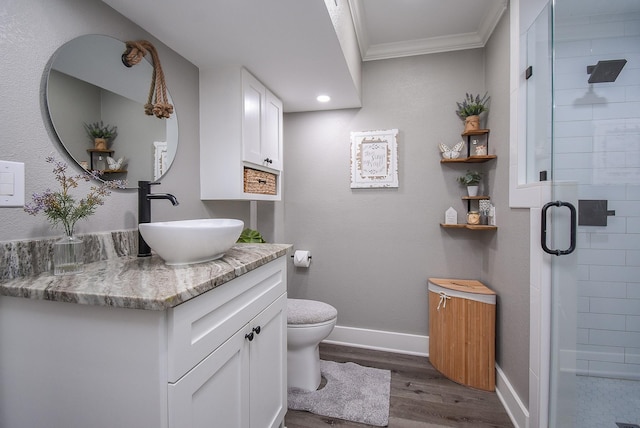 bathroom featuring toilet, crown molding, vanity, a shower with door, and hardwood / wood-style floors