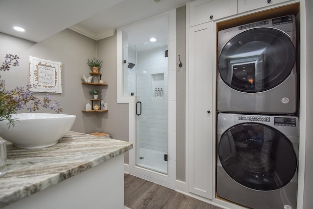 laundry room featuring ornamental molding, sink, stacked washer / drying machine, and dark wood-type flooring