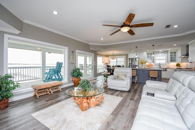 living room with ceiling fan, ornamental molding, and light wood-type flooring