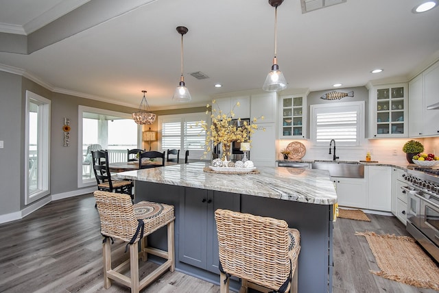 kitchen with double oven range, a center island, sink, and white cabinets