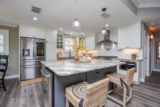 kitchen with white cabinets, appliances with stainless steel finishes, wall chimney range hood, and beverage cooler