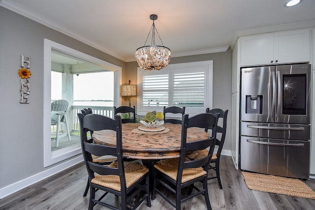 dining area with hardwood / wood-style flooring, ornamental molding, and a notable chandelier