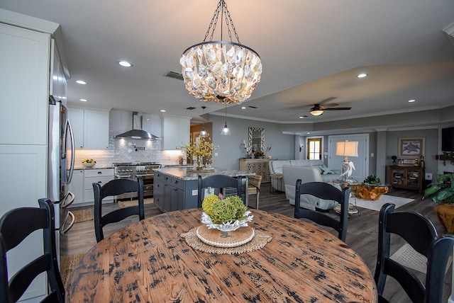 dining space with crown molding, dark wood-type flooring, and ceiling fan with notable chandelier