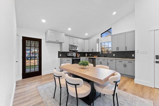 kitchen with stainless steel appliances, gray cabinetry, light hardwood / wood-style floors, and decorative backsplash