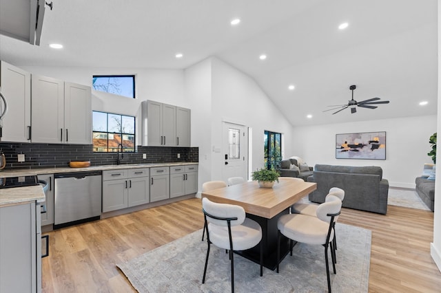 dining space featuring ceiling fan, sink, high vaulted ceiling, and light hardwood / wood-style floors