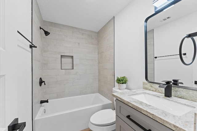 full bathroom with vanity, tiled shower / bath, a textured ceiling, and toilet