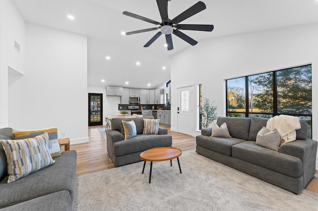 living room featuring ceiling fan, high vaulted ceiling, and light hardwood / wood-style floors