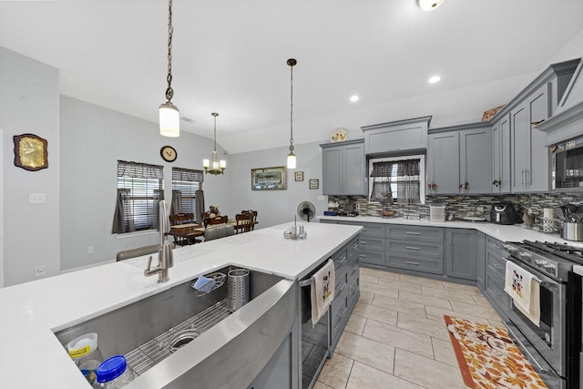 kitchen featuring pendant lighting, dishwashing machine, gray cabinets, backsplash, and stainless steel gas range oven