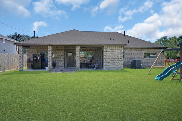 back of house featuring central AC unit, a lawn, a patio, and a playground