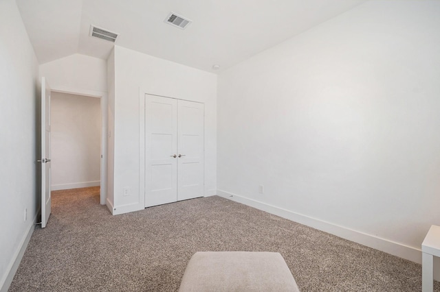 unfurnished bedroom with lofted ceiling, carpet floors, and a closet