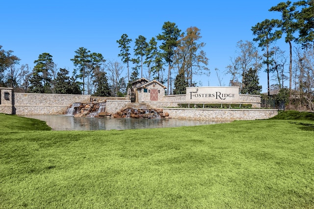 community sign featuring a water view and a yard