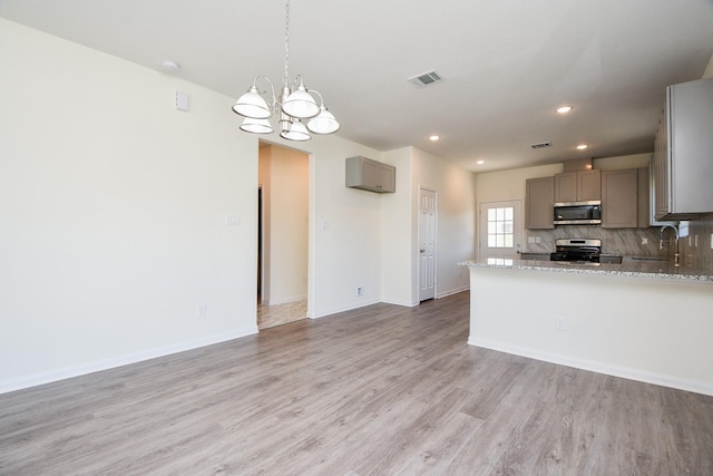 kitchen featuring tasteful backsplash, gray cabinets, stainless steel appliances, light stone countertops, and light hardwood / wood-style floors