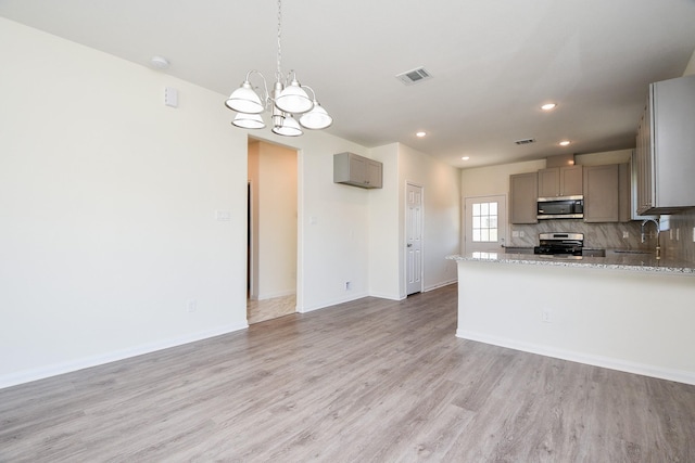 kitchen featuring light stone counters, tasteful backsplash, light hardwood / wood-style flooring, appliances with stainless steel finishes, and gray cabinets