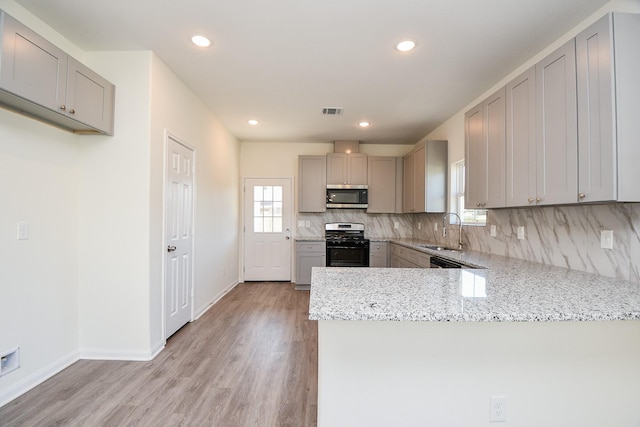 kitchen featuring sink, gray cabinetry, kitchen peninsula, stainless steel appliances, and backsplash