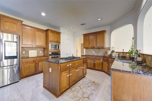 kitchen with sink, tasteful backsplash, a center island, dark stone countertops, and appliances with stainless steel finishes