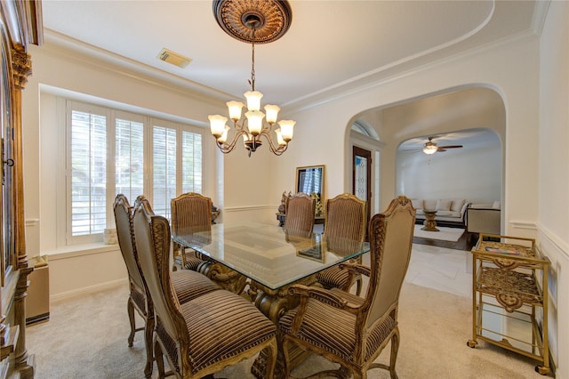 carpeted dining space featuring crown molding and ceiling fan with notable chandelier