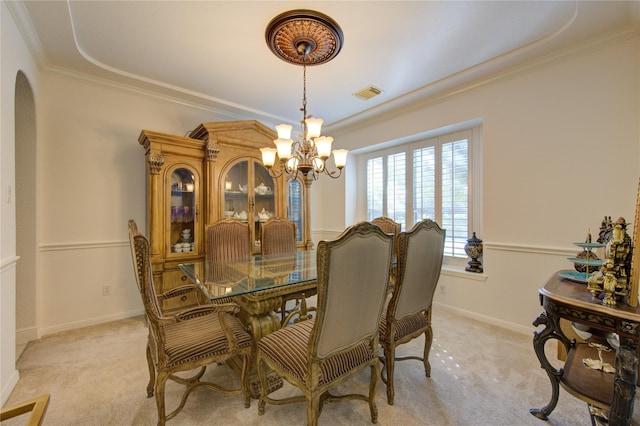 dining area featuring light carpet, crown molding, and a chandelier