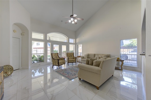 living room with a towering ceiling, french doors, and ceiling fan