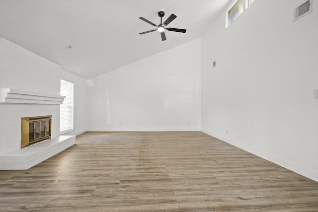 unfurnished living room with ceiling fan, high vaulted ceiling, a fireplace, and light hardwood / wood-style flooring