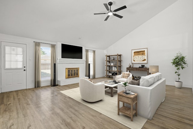 living room featuring a brick fireplace, hardwood / wood-style flooring, high vaulted ceiling, and ceiling fan