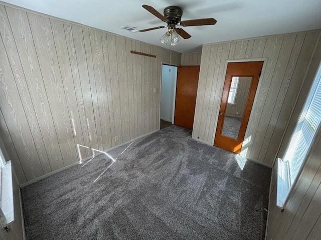 carpeted empty room featuring ceiling fan and wood walls