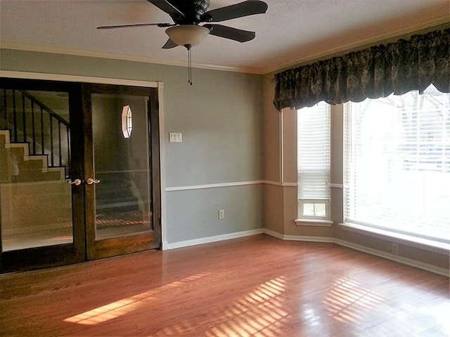 unfurnished room featuring ceiling fan, ornamental molding, wood-type flooring, and a wealth of natural light