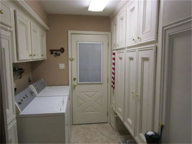 washroom featuring cabinets and washer and clothes dryer