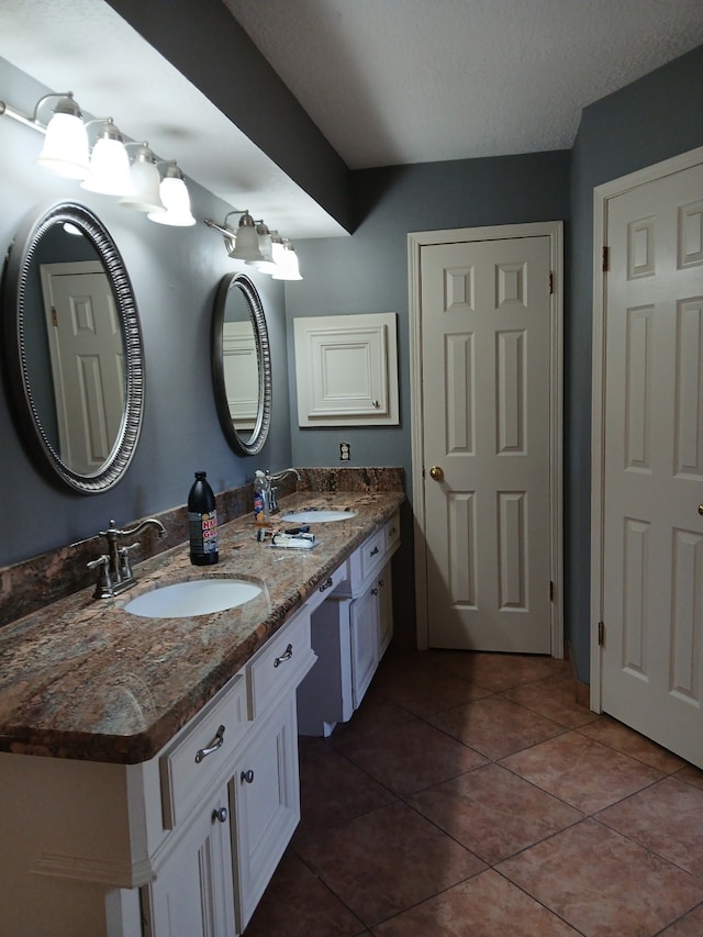 bathroom with tile patterned flooring, vanity, and a textured ceiling