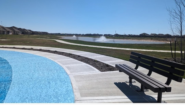 view of pool with a yard and a water view