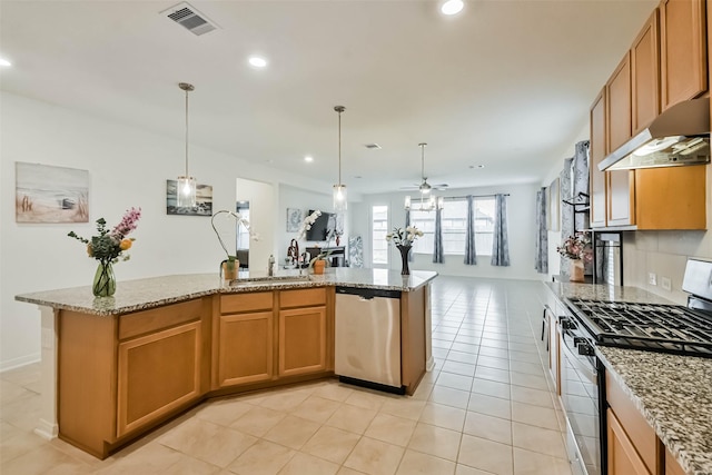 kitchen featuring appliances with stainless steel finishes, decorative light fixtures, a center island, light tile patterned floors, and light stone counters