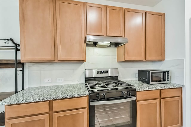 kitchen featuring tasteful backsplash, light stone countertops, and gas range oven