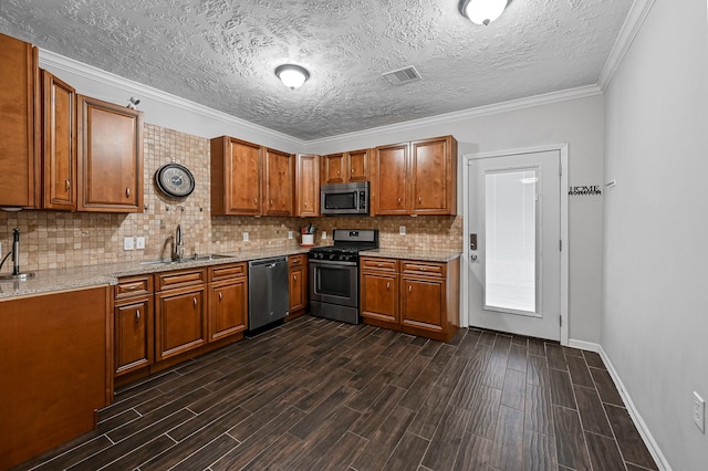 kitchen with sink, appliances with stainless steel finishes, light stone counters, ornamental molding, and a textured ceiling