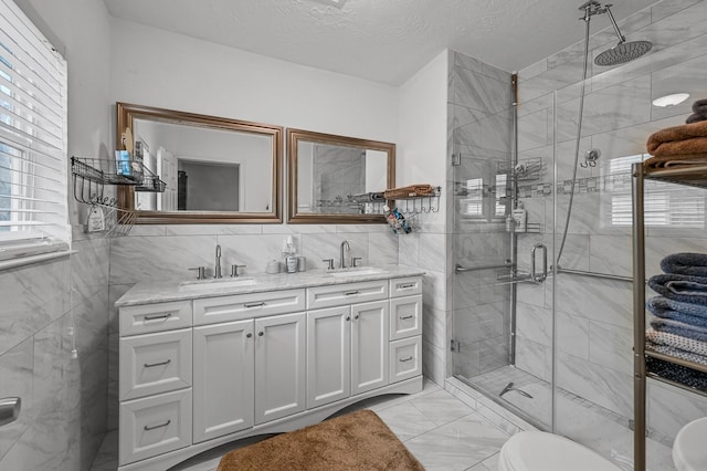 bathroom featuring vanity, a shower with shower door, tile walls, and a textured ceiling