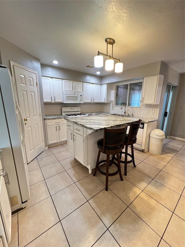 kitchen featuring white cabinetry, fridge, a center island, and decorative light fixtures