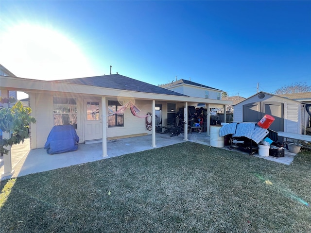 rear view of property featuring a lawn, a patio area, and a storage unit