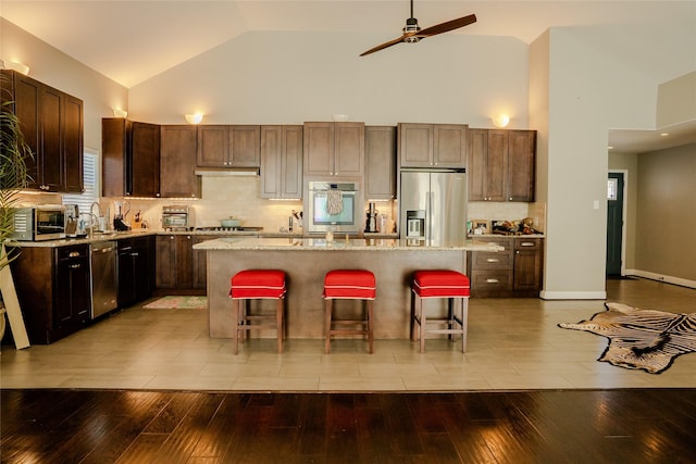 kitchen with appliances with stainless steel finishes, a center island, a breakfast bar area, and light hardwood / wood-style flooring