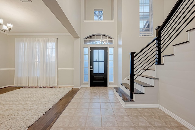 foyer entrance with crown molding, plenty of natural light, and a notable chandelier