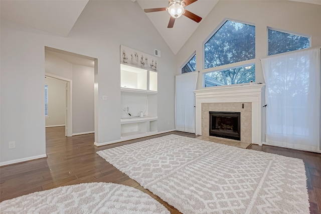 unfurnished living room featuring hardwood / wood-style flooring, ceiling fan, high vaulted ceiling, and a tile fireplace