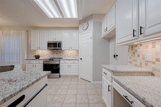 kitchen featuring tasteful backsplash, stainless steel appliances, light stone countertops, and white cabinets