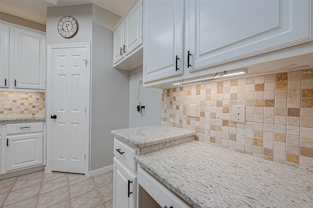 kitchen with white cabinetry, decorative backsplash, light stone countertops, and light tile patterned flooring