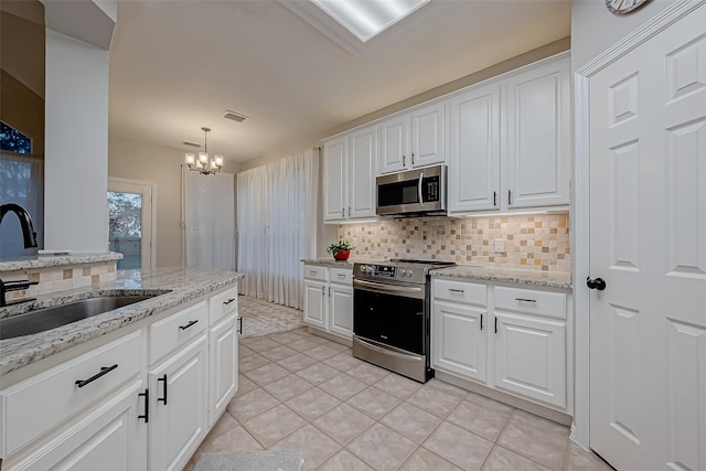 kitchen with sink, tasteful backsplash, light tile patterned floors, appliances with stainless steel finishes, and white cabinets