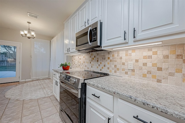 kitchen featuring appliances with stainless steel finishes, white cabinetry, decorative backsplash, light tile patterned floors, and light stone counters