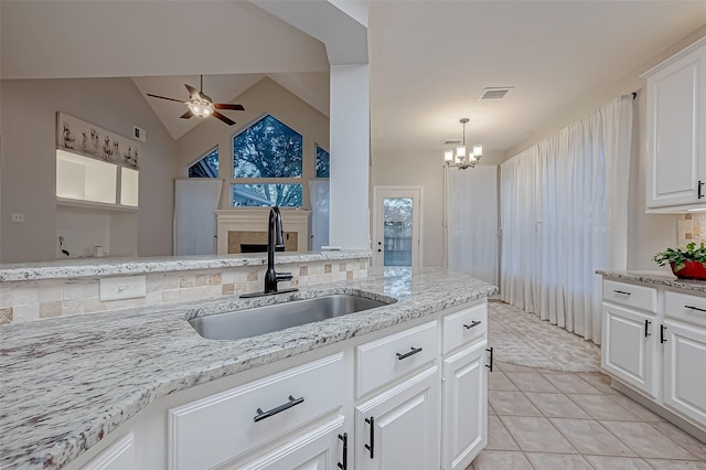 kitchen with white cabinetry, vaulted ceiling, sink, and light tile patterned floors