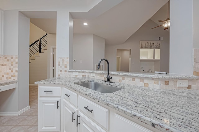 kitchen with sink, light tile patterned floors, backsplash, light stone counters, and white cabinets