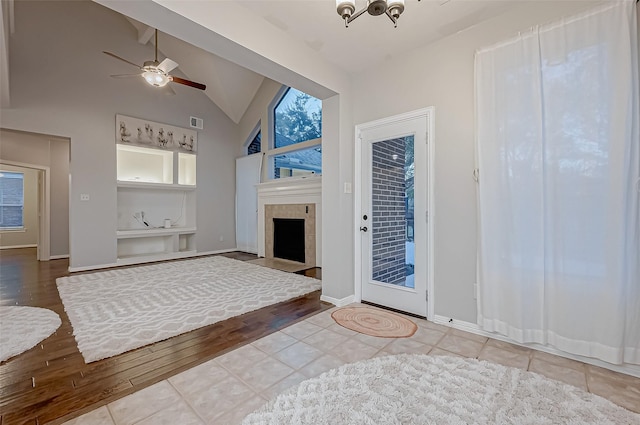 entryway featuring lofted ceiling, light tile patterned floors, a tile fireplace, and ceiling fan