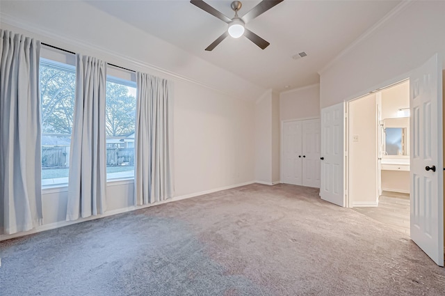 unfurnished bedroom with vaulted ceiling, ornamental molding, light colored carpet, and ceiling fan