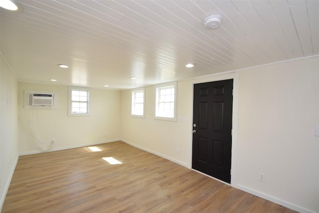 basement featuring wood ceiling, crown molding, light hardwood / wood-style floors, and a wall unit AC